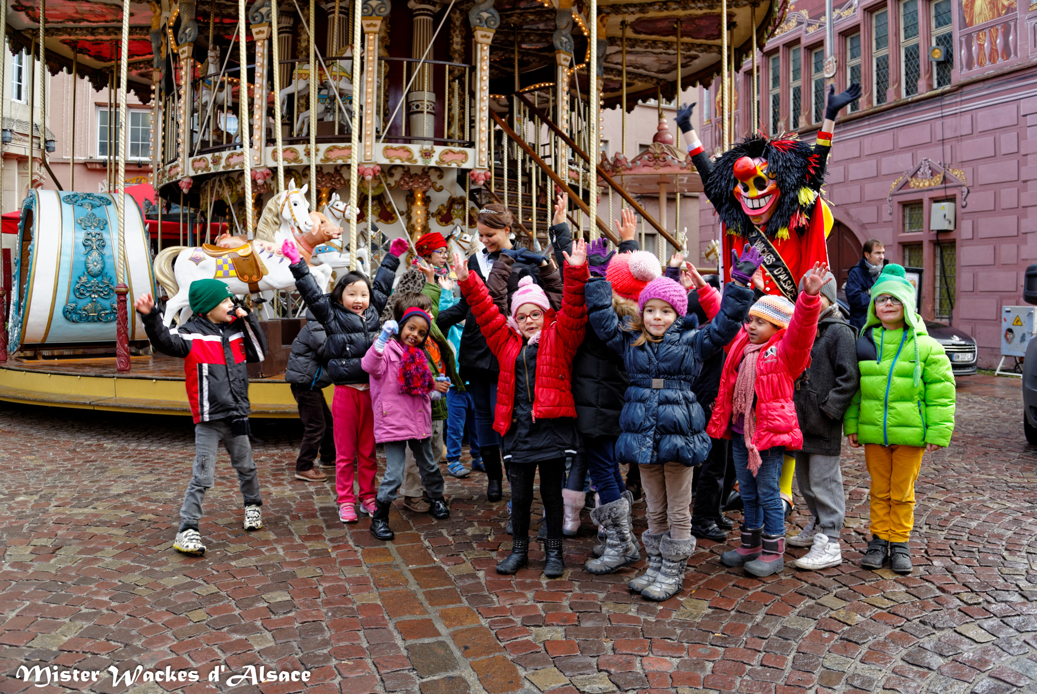 Téléthon Mulhouse 2013, Mister Wackes d’Alsace entouré de jeunes supporter devant le manège sur la Place de la Réunion à Mulhouse